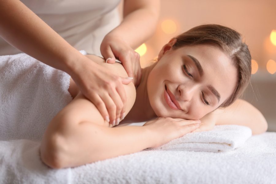 A woman relaxing on a massage table while a therapist works on her shoulder