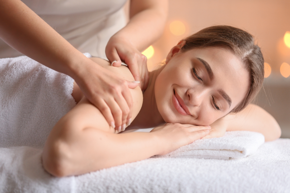 A woman relaxing on a massage table while a therapist works on her shoulder